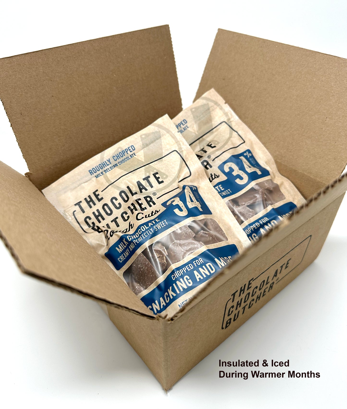An open box holds several bags of My Store Belgian Chocolate — Roughly Chopped 34% Milk Chocolate, ideal for snacking. Insulated & Iced During Warmer Months appears in the bottom right corner to help prevent melting.