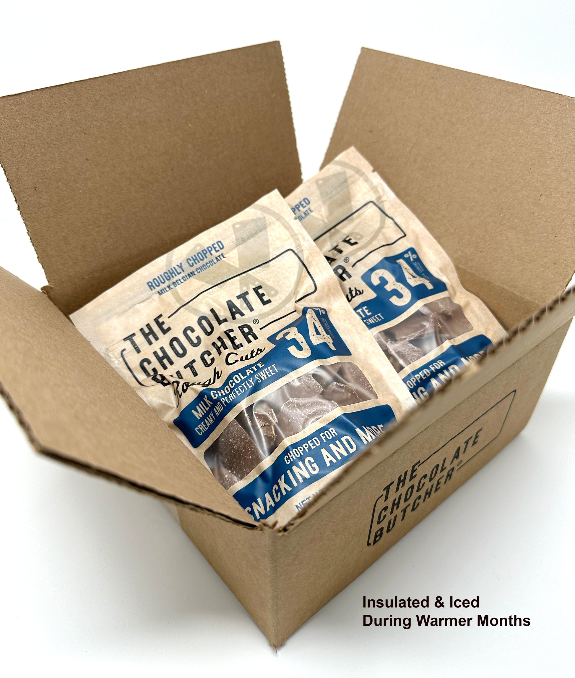 An open box holds several bags of My Store Belgian Chocolate — Roughly Chopped 34% Milk Chocolate, ideal for snacking. Insulated & Iced During Warmer Months appears in the bottom right corner to help prevent melting.