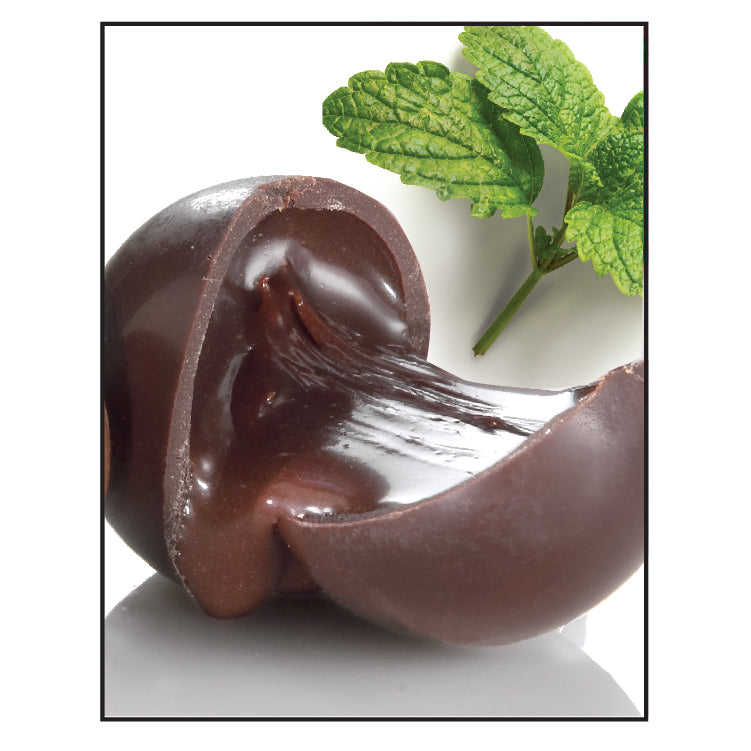 The Chocolate Butcher Dark Chocolate Mint Truffle is sliced open to reveal creamy ganache and glossy mint filling inside, with fresh green mint leaves shown in the background.