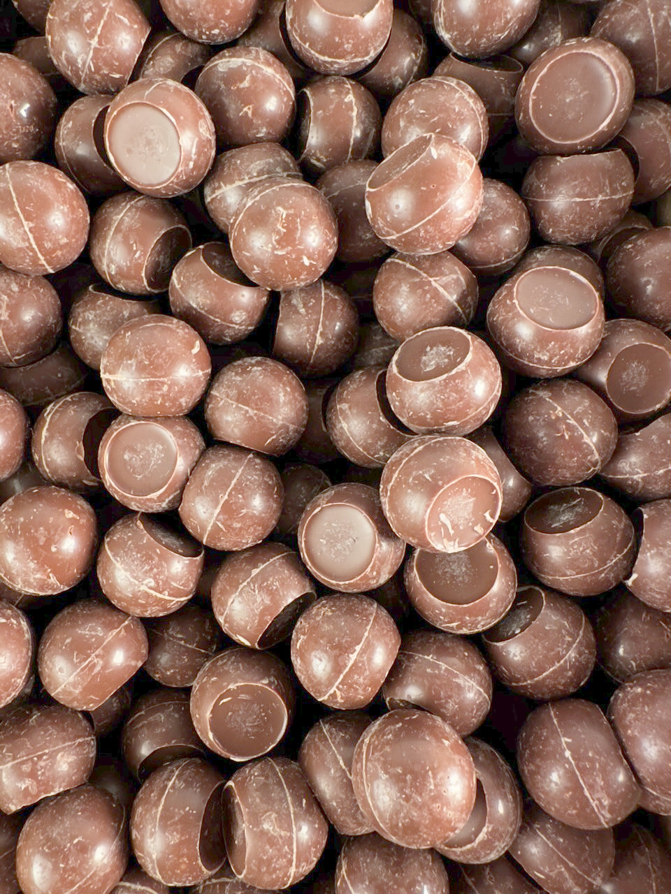 A large pile of The Chocolate Butcher Milk Chocolate Caramel Truffles are closely packed together, ready to be eaten with a smooth caramel center.